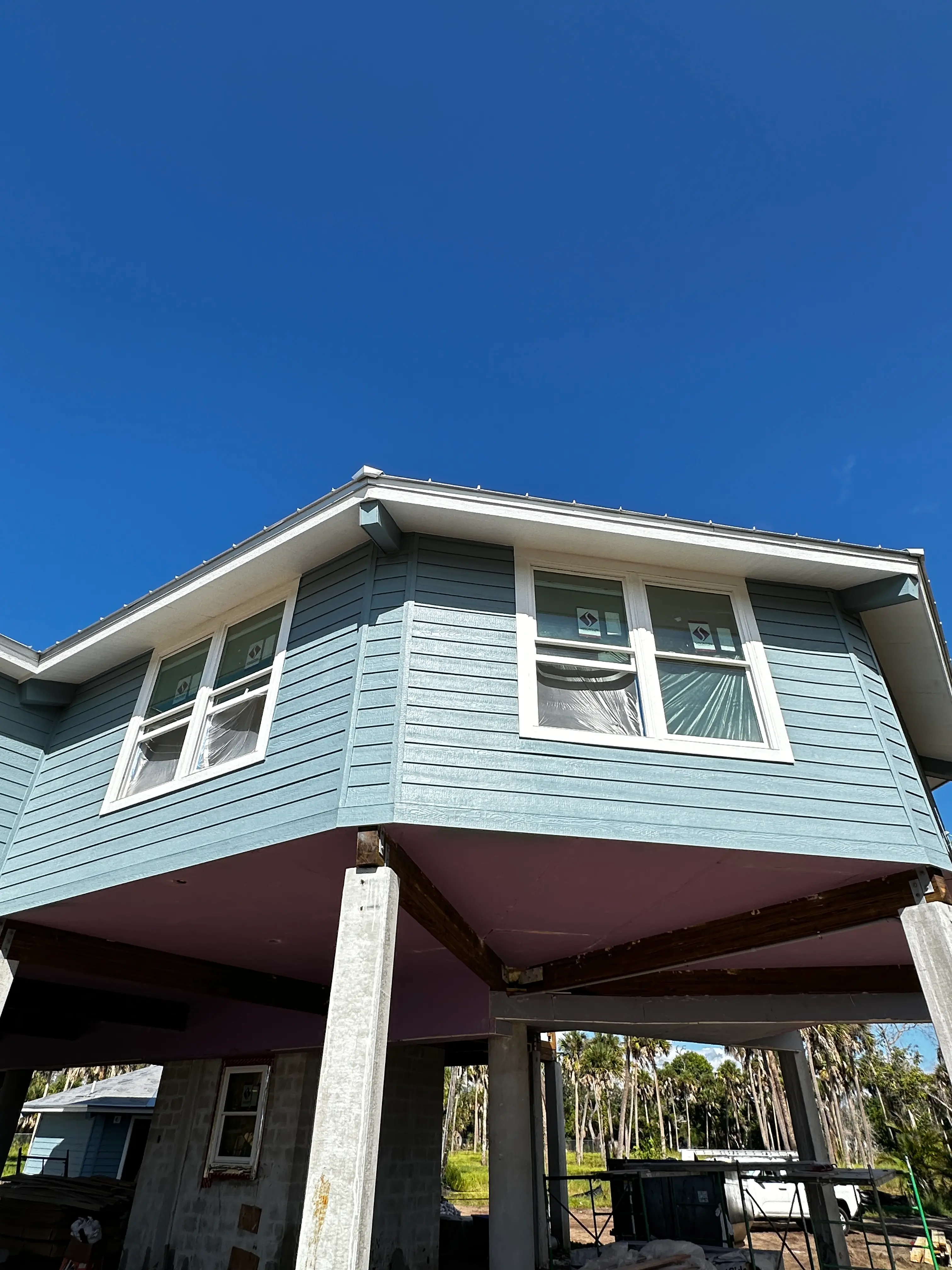 Two-story exterior paint job in progress with fresh blue siding and white trim